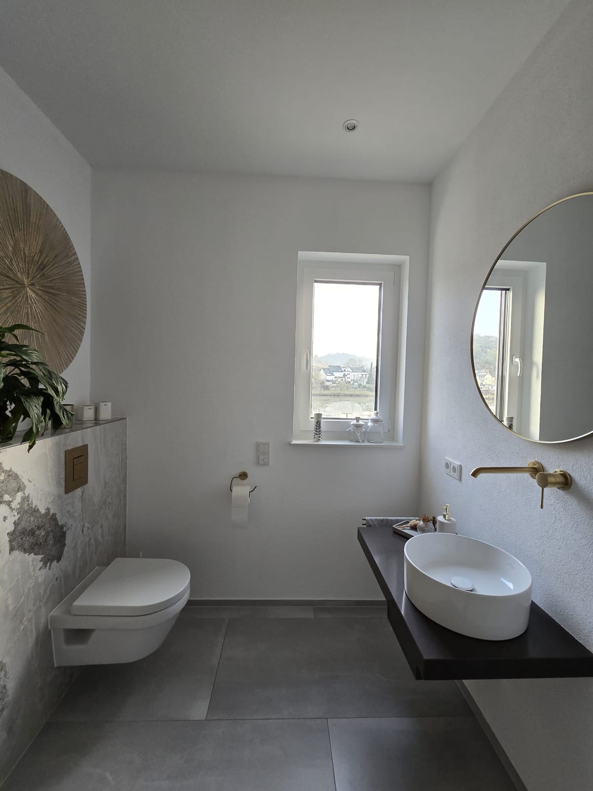 Helles Gäste-WC mit Aufsatzbecken, Rundspiegel und Fensterblick ins Moseltal