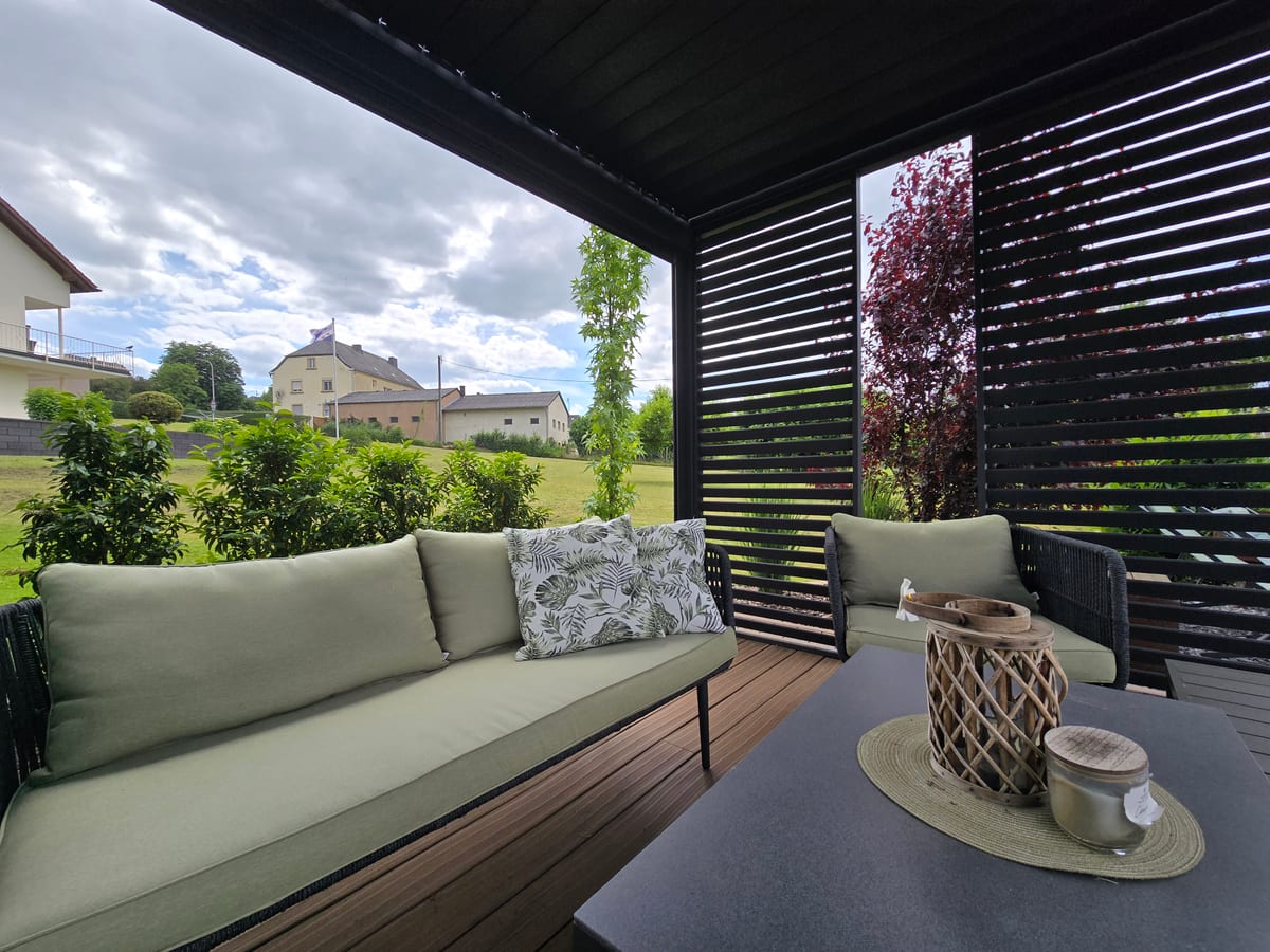 Überdachte Terrasse mit Loungemöbeln und Sichtschutz aus dunklen Holzlamellen